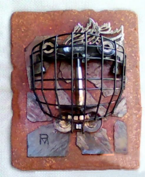 Street hockey: broken slate on particle bardHair: parts from a fondue cooker.Nose: Flatware knife handleMouth: Tension adjuster -office chairTeeth: nutsEyes: larger nuts mounted in very large split washers mounted on part of a bicycle seat.